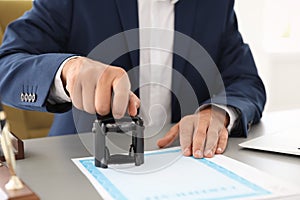 Notary stamping document at desk in office