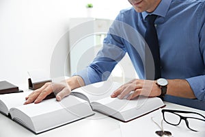 Notary studying law books at table in office