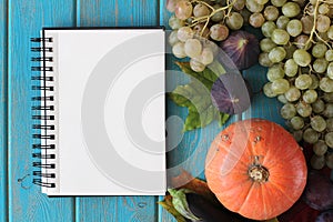 Note book and composition of vegetables on blue wooden desk.