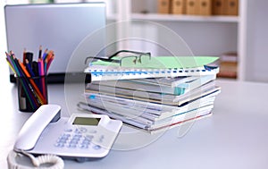 A note book, laptop, pen, graph paper document on the office desk table behind white blind