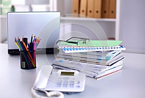 A note book, laptop, pen, graph paper document on the office desk table behind white blind