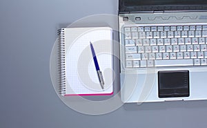 A note book, laptop, pen, graph paper document on the office desk table behind white blind