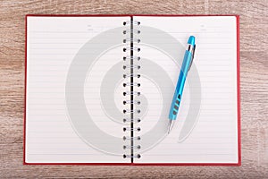 Note or diary book and blue pen put on wooden table