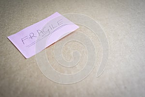 Note `fragile` on a pink sticker on a cardboard surface.