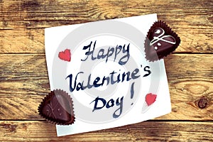 Note with greeting valentines day, two chocolate candy heart