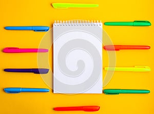 Note pad with empty space for text, colorful felt tip pens around on yellow background