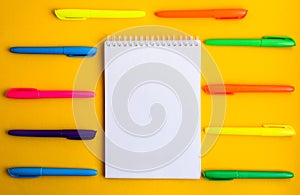 Note pad with empty space for text, colorful felt tip pens around on yellow background