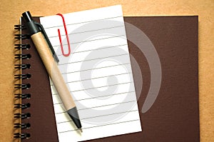 Note paper clip on notebook with pen