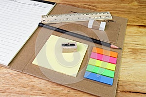 Note paper colour and pencil eraser ruler with book on wood table