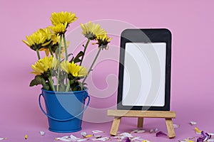 Note paper with frame and and flowers in blue bucket on pink background.