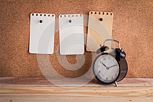 Note papers on cork board with alarm clock