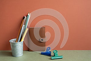 Note, pencil holder, clip on khaki desk. red wall background. workspace, office supply