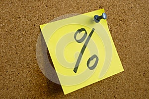 A note with a percent sign as a symbol of profit is pinned to an office board.