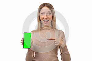 Note that. Pretty young blond woman is pointing finger at mobile phone blank screen in her hand