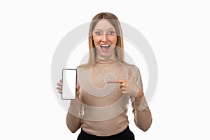 Note that. Pretty young blond woman is pointing finger at mobile phone blank screen in her hand