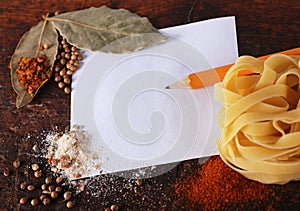 Note,spices and pasta on a wood cutting board