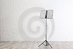 Note stand with music sheets near brick wall. Space for text