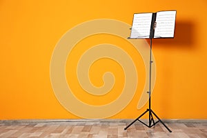 Note stand with music sheets near color wall indoors.