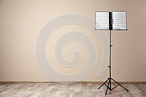 Note stand with music sheets near color wall indoors.