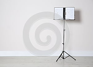 Note stand with music sheets near white wall. Space for text