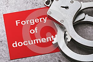 A note with text and handcuffs on the table, a major plan. Concept on the punishment of forgery of documents