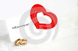 A note, wedding rings and a red heart