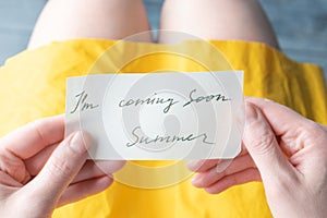 A note written in pen and ink on behalf of summer I'm coming soon in the hands of a girl.