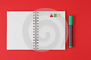 Notebook with ABC letters and colored markers on a red background