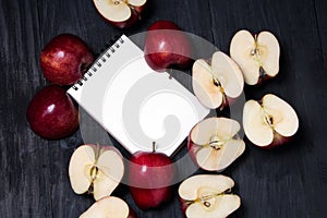 Notebook and apple on a black wooden background top view