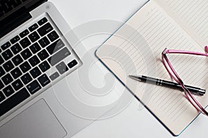 Notebook with black pen, Colorful notepads on the desk, Glasses on the desk with pen and cup of coffee, Computer keyboard with col