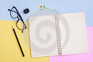 Notebook ,Black pencil,Eyeglasses,Eraser and White Flower on Pink,Yellow and Blue Background