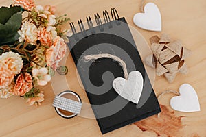 Notebook with black sheets with copy space, bouquet of flowers and a white heart