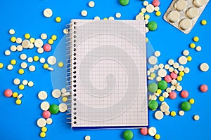 Notebook on a blue background and many different pills