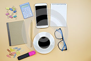 Notebook brown cover mobile phone calculator and black coffee white cup blue glasses on orange background pastel style with