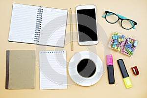 Notebook brown cover mobile phone calculator and black coffee white cup green glasses on orange background pastel style with copy