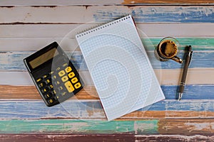 Notebook calculator and pen with cup of coffee on top view work space, office desk