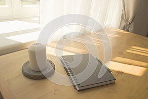 Notebook and candle on a table.