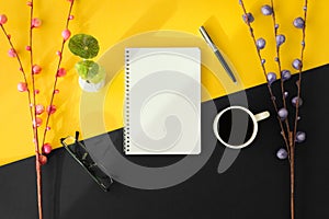 Notebook and coffee cup on black and yellow background.