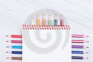 Notebook with colored pencils lie beautifully on a light background