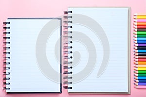 Notebook and colored pencils on pink background