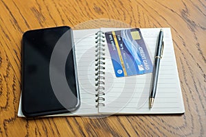 Notebook, credit card and touchscreen smartphone on table. business, lifestyle, technology, ecommerce and online payment concept