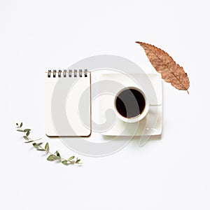 Notebook, cup of coffee with leaves on white background