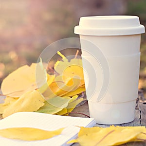 Notebook, cup of coffee and yellow autumn leaves