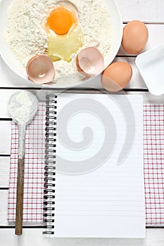 Notebook, egg, flour and spoon