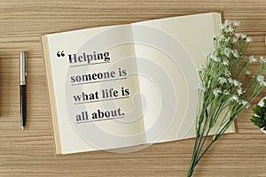 Notebook with flower on wood background with quote