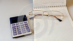 Notebook with glasses and calculator on a light background