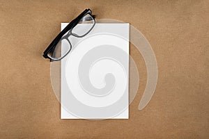 A notebook with glasses in a minimal style top view isolated on brown background of recycled craft vintage paper