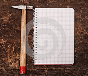 Notebook and hammer on the wooden table