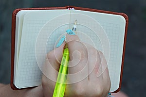 notebook in hand with a girl pen writing in green