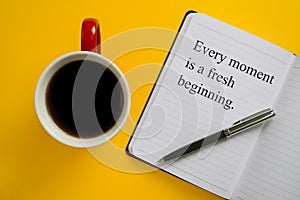 Notebook with inspirational quote with pen and coffee mug. Every Moment is a Fresh Beginning.